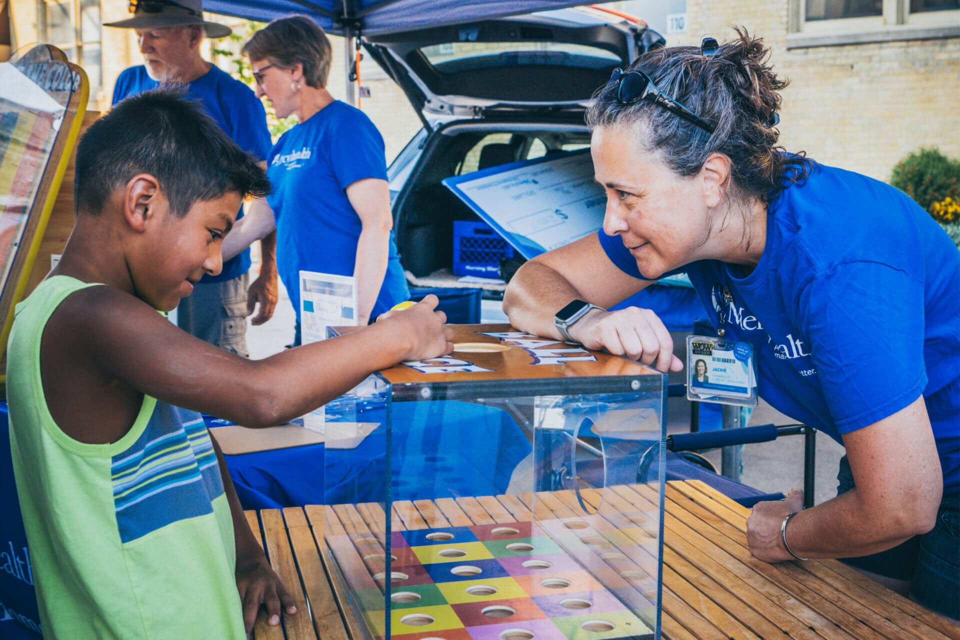 A Mercyhealth volunteer helps a young boy play a game during a festival in downtown Janesville